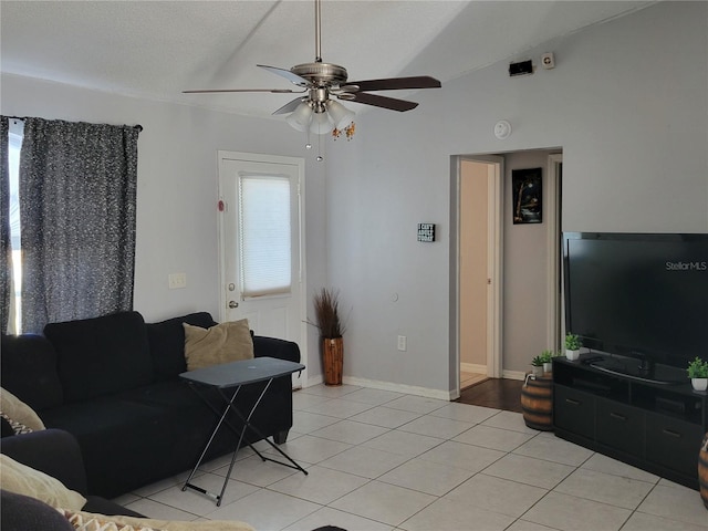 living area featuring light tile patterned floors, lofted ceiling, ceiling fan, a textured ceiling, and baseboards