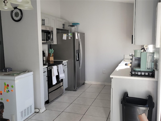 kitchen with light tile patterned floors, stainless steel appliances, light countertops, white cabinetry, and baseboards