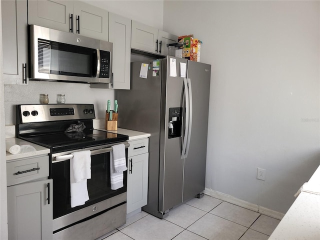 kitchen with light tile patterned floors, stainless steel appliances, light countertops, and baseboards