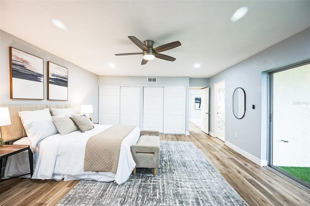 bedroom featuring baseboards, visible vents, wood finished floors, multiple closets, and recessed lighting