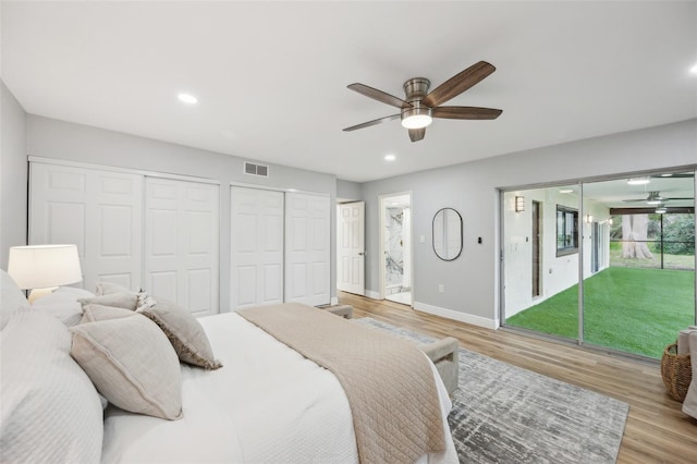 bedroom with light wood-style flooring, two closets, visible vents, and baseboards