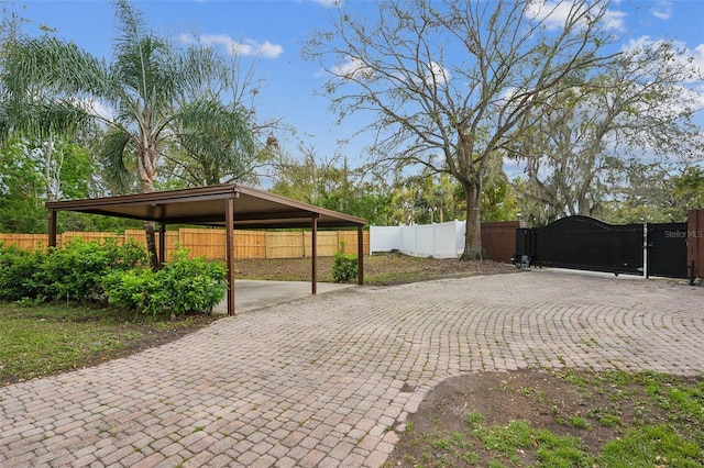 view of parking featuring driveway, fence, and a gate