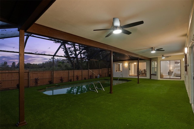 view of yard featuring a ceiling fan, glass enclosure, a fenced backyard, and a fenced in pool