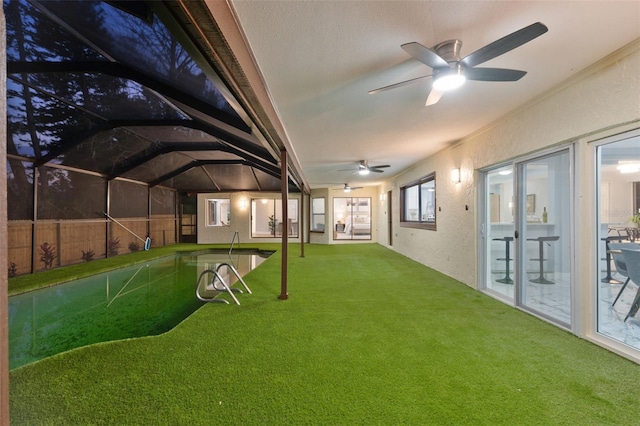 view of yard with a ceiling fan, a lanai, and fence