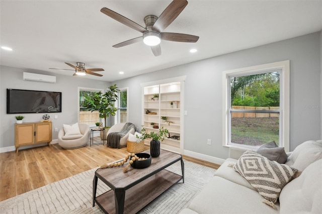 living room featuring ceiling fan, recessed lighting, baseboards, light wood finished floors, and a wall mounted air conditioner