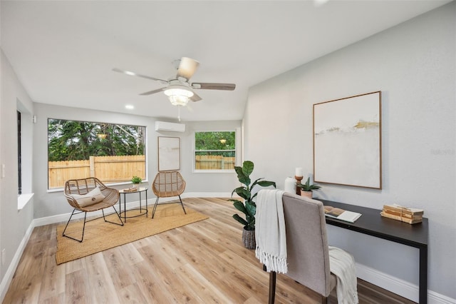 office space with a ceiling fan, baseboards, an AC wall unit, and wood finished floors