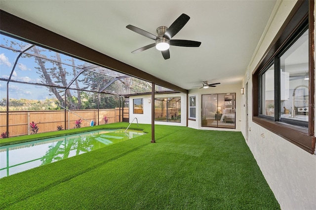 view of yard with a lanai, ceiling fan, fence, and a fenced in pool