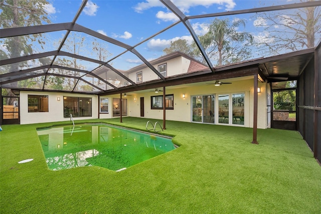 exterior space with a patio, stucco siding, a lawn, a ceiling fan, and glass enclosure