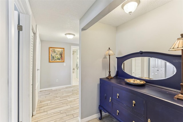 interior space with a textured ceiling, baseboards, and wood tiled floor