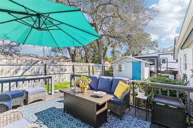 wooden terrace featuring an outdoor hangout area, a shed, an outdoor structure, and fence