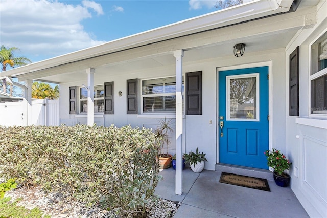 entrance to property featuring covered porch and fence