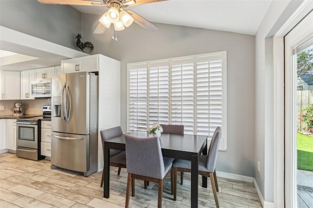 dining space featuring lofted ceiling, light wood-style floors, ceiling fan, and baseboards