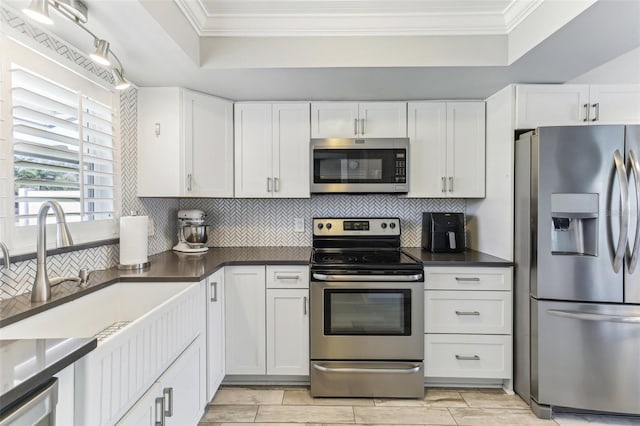 kitchen featuring stainless steel appliances, white cabinetry, crown molding, and decorative backsplash