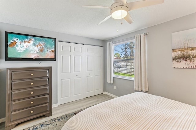 bedroom with a textured ceiling, ceiling fan, wood finished floors, baseboards, and a closet