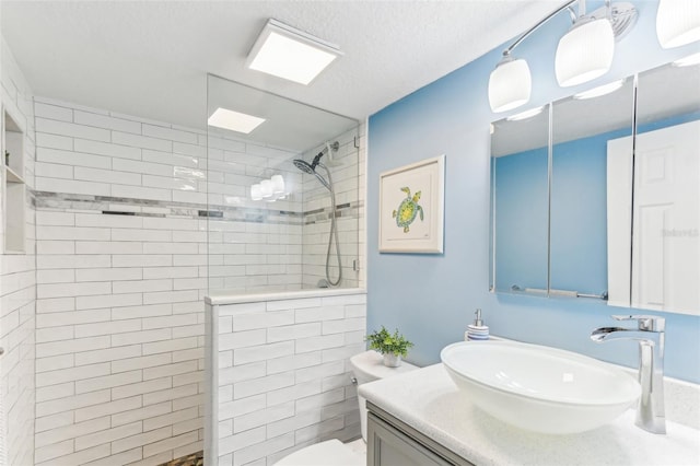 full bathroom with a textured ceiling, vanity, toilet, and walk in shower