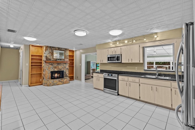 kitchen featuring a fireplace, a sink, open floor plan, appliances with stainless steel finishes, and dark countertops