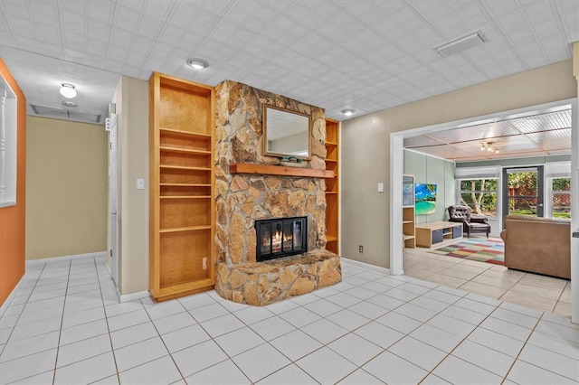 living room featuring built in shelves, a fireplace, light tile patterned floors, visible vents, and baseboards