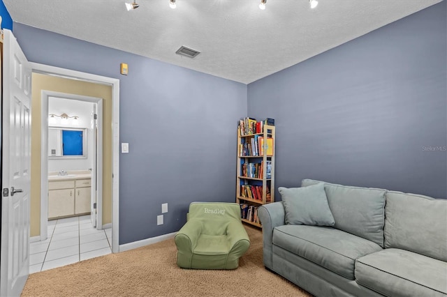 sitting room with baseboards, visible vents, light colored carpet, a textured ceiling, and light tile patterned flooring