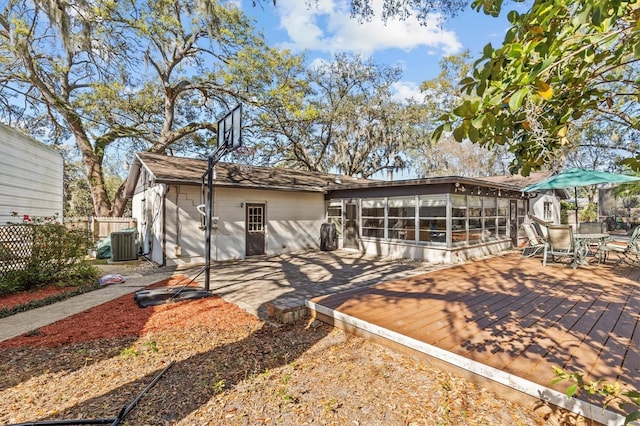 view of front of home with a sunroom, fence, a deck, central AC, and outdoor dining space