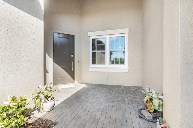 view of exterior entry featuring a patio and stucco siding