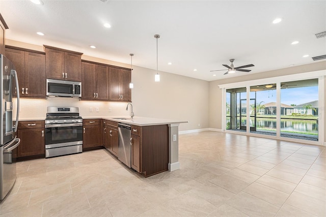 kitchen with tasteful backsplash, appliances with stainless steel finishes, a sink, dark brown cabinets, and a peninsula