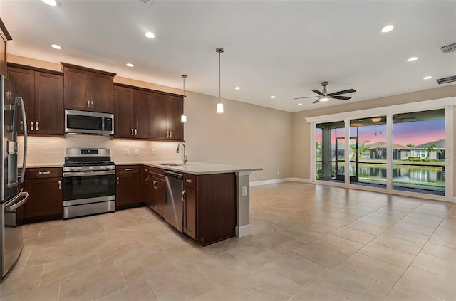 kitchen featuring a peninsula, a sink, open floor plan, appliances with stainless steel finishes, and decorative backsplash