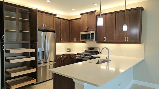 kitchen featuring light countertops, appliances with stainless steel finishes, a peninsula, and backsplash