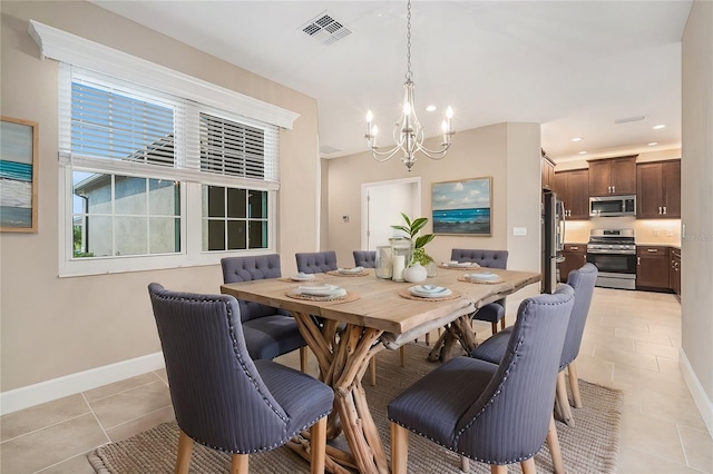 dining room with light tile patterned floors, an inviting chandelier, visible vents, and baseboards