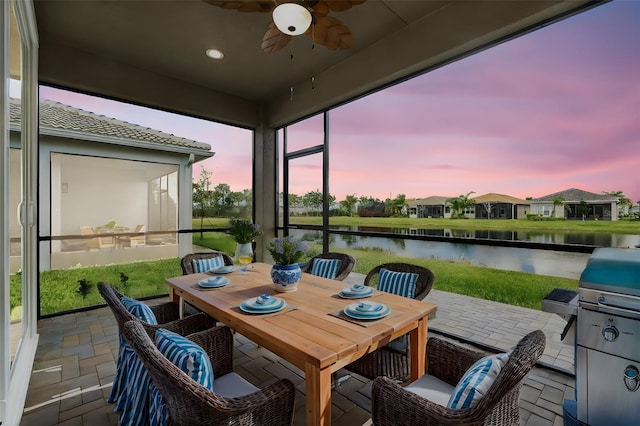 sunroom / solarium featuring a water view and a ceiling fan