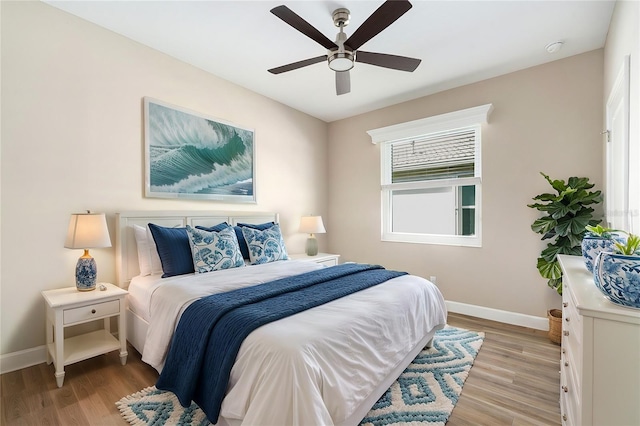 bedroom with light wood-style floors, ceiling fan, and baseboards