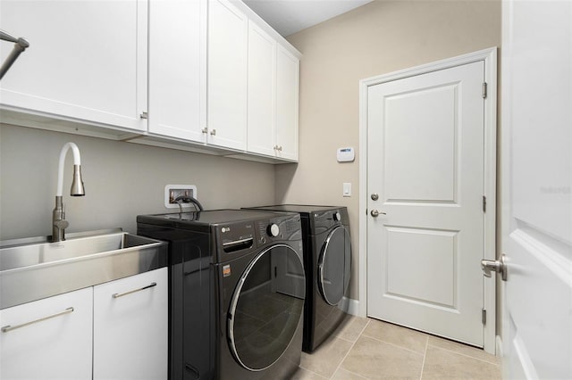 laundry room featuring light tile patterned flooring, a sink, baseboards, cabinet space, and washer and clothes dryer