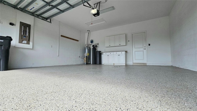 garage with water heater, concrete block wall, and a garage door opener