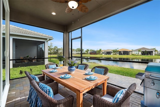 sunroom with a water view and ceiling fan