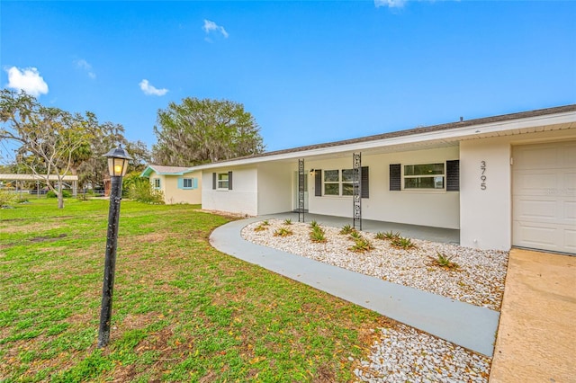 single story home featuring a front lawn, an attached garage, and stucco siding