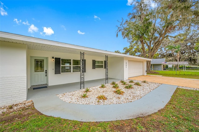 view of front facade with a garage, covered porch, driveway, and stucco siding