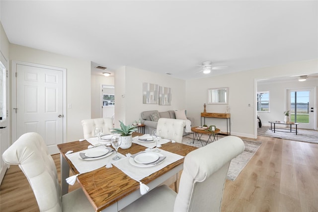 dining area featuring visible vents, a ceiling fan, baseboards, and light wood finished floors