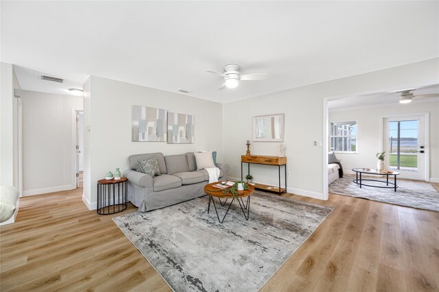 living area with a ceiling fan, wood finished floors, visible vents, and baseboards