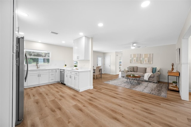 kitchen featuring light wood finished floors, visible vents, open floor plan, stainless steel appliances, and a sink