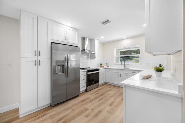 kitchen featuring visible vents, light wood finished floors, a sink, appliances with stainless steel finishes, and wall chimney range hood