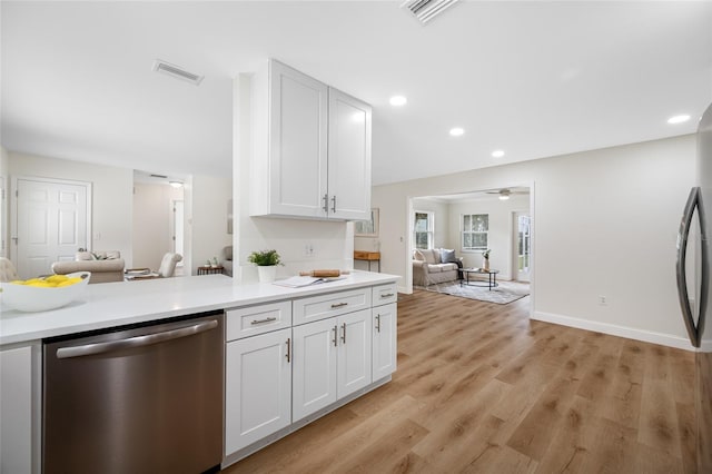 kitchen featuring dishwasher, light countertops, open floor plan, and visible vents