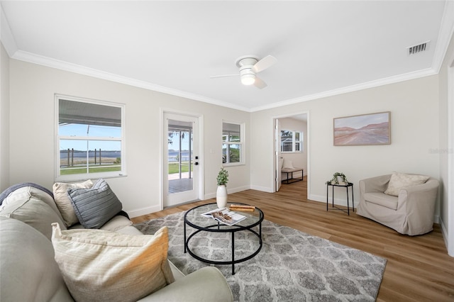 living area with crown molding, wood finished floors, baseboards, and visible vents