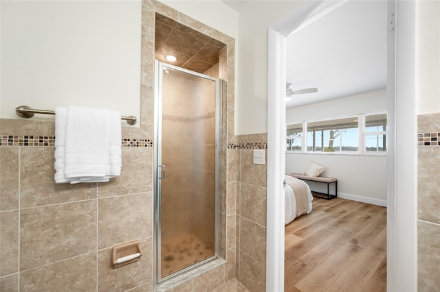 ensuite bathroom featuring a ceiling fan, a shower stall, wood finished floors, and connected bathroom