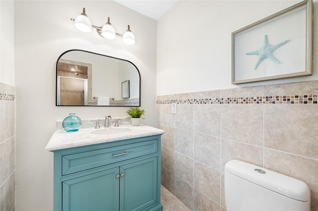 bathroom with toilet, tile walls, and vanity