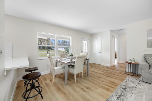 dining area featuring light wood finished floors, visible vents, and baseboards