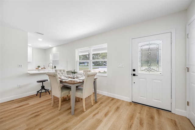 dining space with light wood-style flooring, baseboards, and visible vents