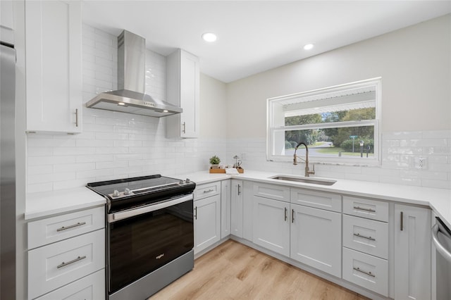 kitchen featuring light countertops, wall chimney exhaust hood, electric stove, and a sink