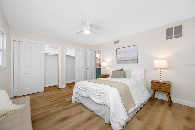 bedroom with light wood finished floors, visible vents, two closets, and baseboards