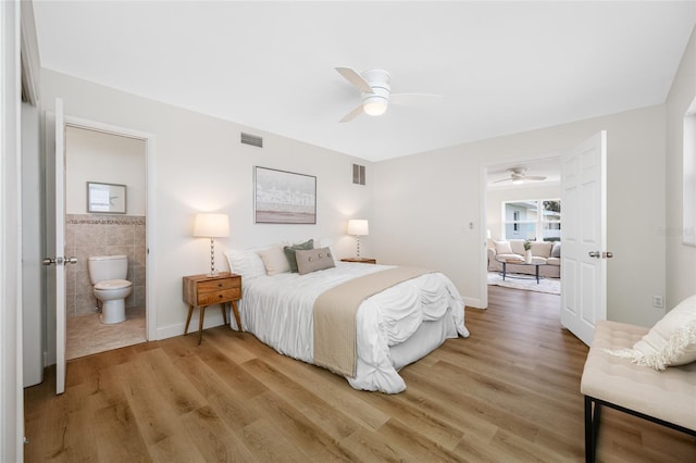 bedroom featuring visible vents, tile walls, connected bathroom, and light wood finished floors