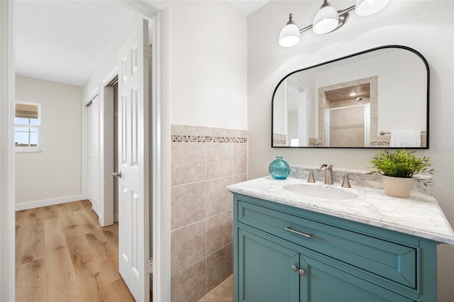 full bathroom with vanity, tile walls, wood finished floors, and a stall shower