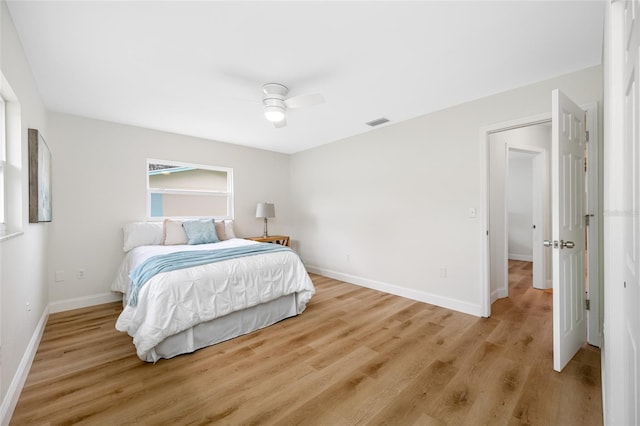 bedroom with ceiling fan, wood finished floors, visible vents, and baseboards